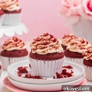Bright red velvet cupcakes on a small white plate with cupcakes behind the plate.