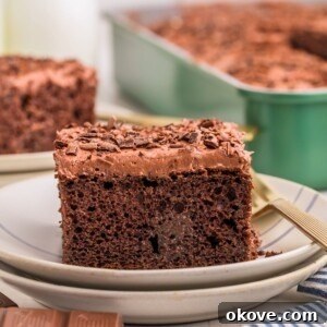 Chocolate poke cake on a plate with bottles of milk behind the plate.
