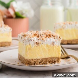 Slice of coconut delight on a small white plate with a fork on the side.