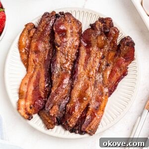 Golden bacon slices on a white plate.