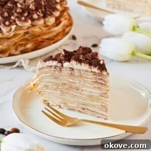 Golden light and fluffy slice of cake make from layers of thin crepes, served on a white plate.