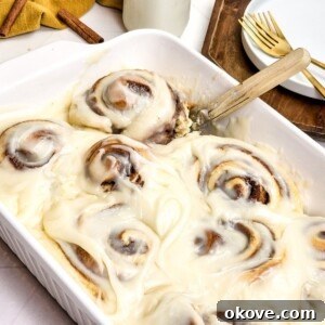 Gooey rolls in a white baking dish with frosting on top.