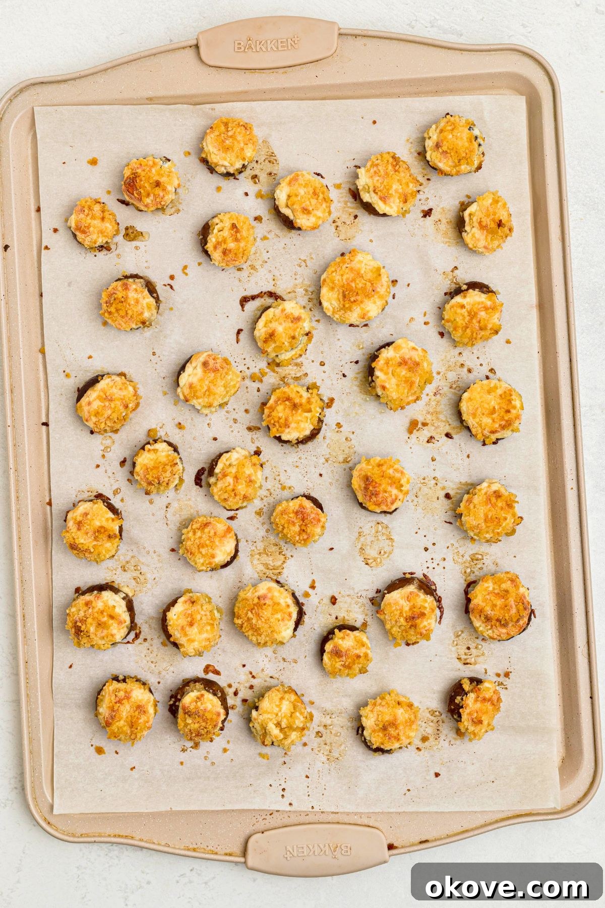Stuffed mushrooms on a baking sheet, lined with parchment paper, after baking. 