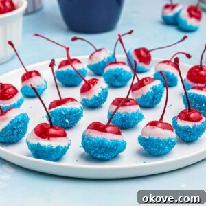 Cherries coated in white chocolate, then dipped in blue sanding sugar, on a white round plate.