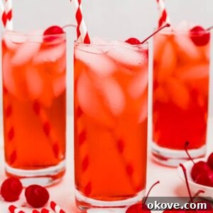 Fourth of July Recipes for a Memorable BBQ & Fireworks Night 27 Bright red drink in a tall glass with ice and cherries on the table.