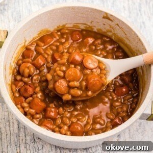 Fourth of July Recipes for a Memorable BBQ & Fireworks Night 32 Close up photo of beans and weenies in a saucepan with a large spoon in the center.