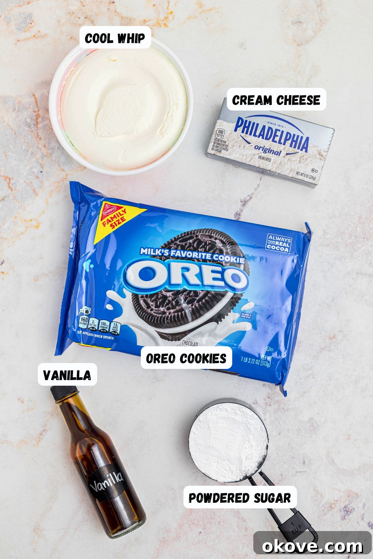 Creamy Oreo Dessert Dip for Parties and Snacks 3 Oreos, powdered sugar, vanilla, cream cheese, and cool whip, on a white marble table.