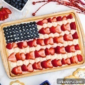 Rectangle cookie topped with frosting, blueberries and strawberries.