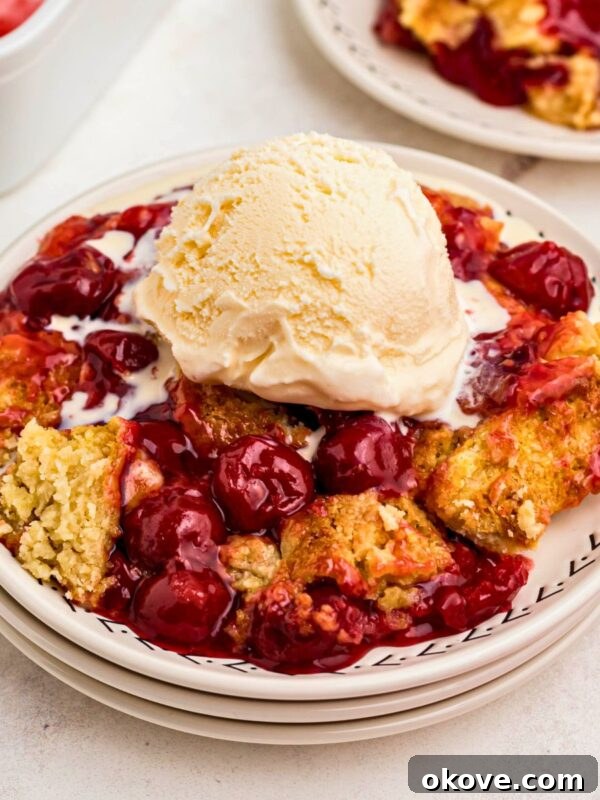 Irresistible Peach Dump Cake Recipe for Summer Desserts 12 Golden crusted cherry dump cake on white plates topped with vanilla ice cream.