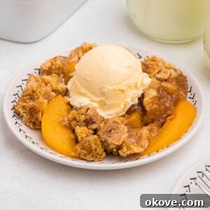 Irresistible Peach Dump Cake Recipe for Summer Desserts 13 Peach cobbler scooped out and served on a small plate, in front of the whole dish, with blue striped straws and cinnamon sticks on the table.