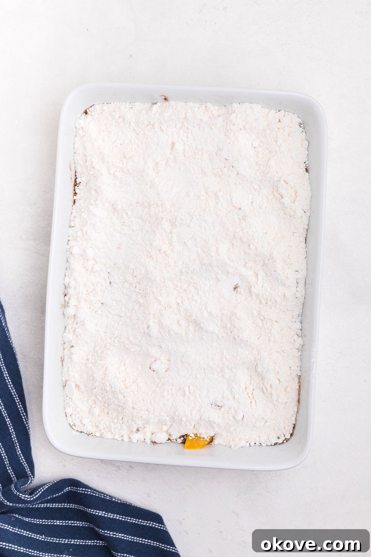 Irresistible Peach Dump Cake Recipe for Summer Desserts 5 Cake mix powder, spread out over peaches, in a a white rectangle dish.