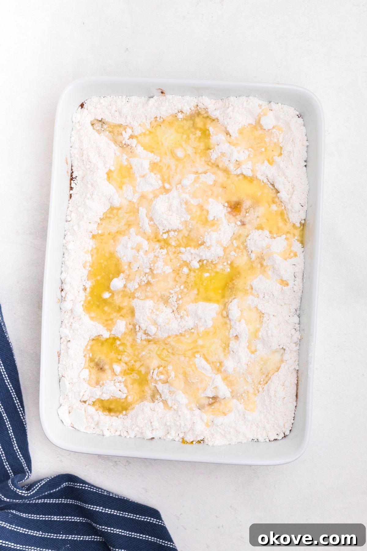 Irresistible Peach Dump Cake Recipe for Summer Desserts 6 Peaches in a white rectangle dish, covered in box cake mix, drizzled with melted butter.