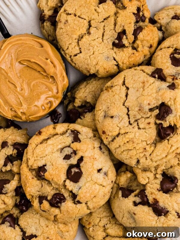 Classic Peanut Butter Blossom Cookies with Chocolate Kiss 8 Peanut butter chocolate chip cookies on a white plate with a scoop of peanut butter next the cookies.