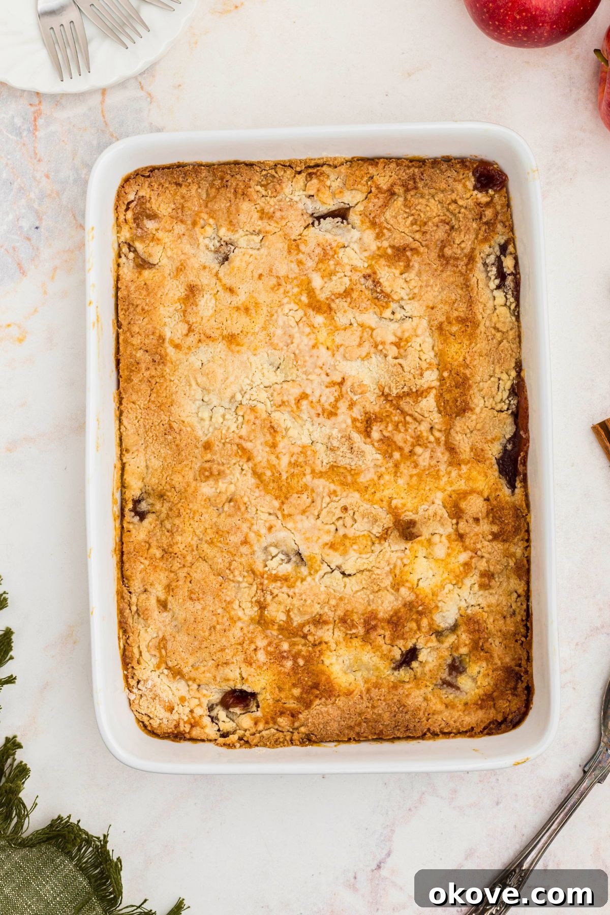 Golden brown crusted apple dump cake in a white baking dish on a marble table.
