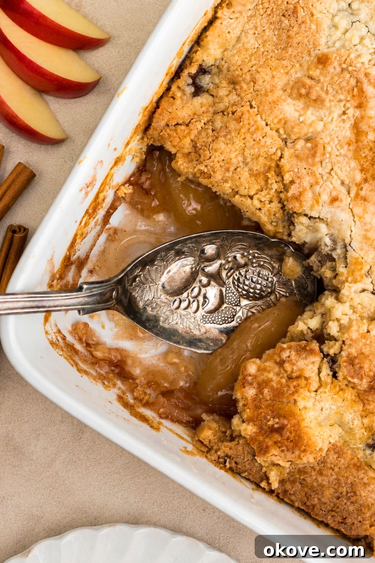 Golden brown crusted apple dump cake in a white baking dish on a marble table.