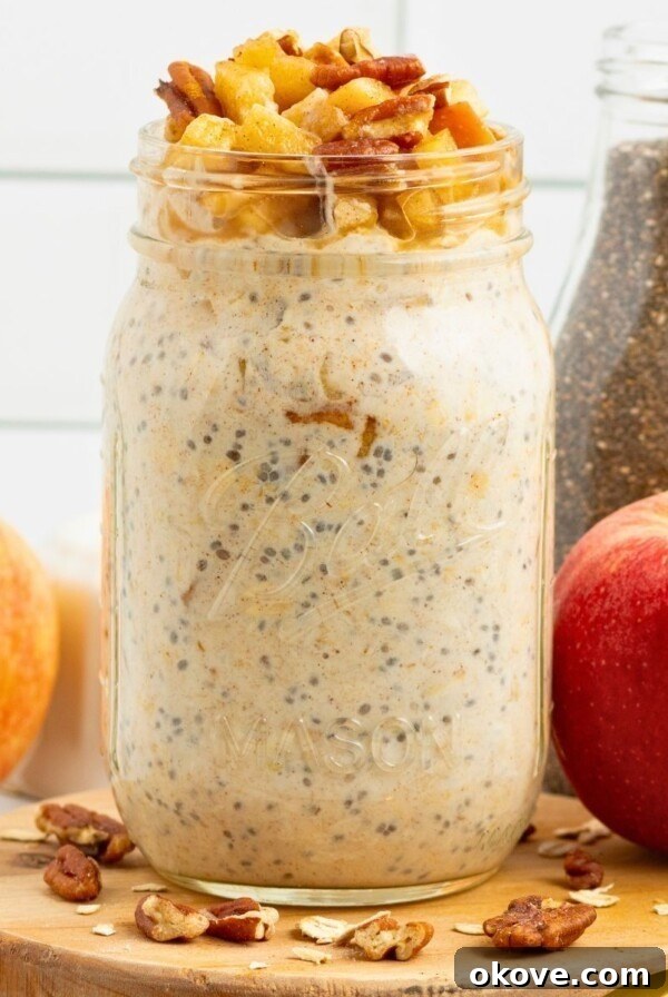 Creamy yogurt mixed with oats and apple slices in a mason jar making apple pie overnight oats.