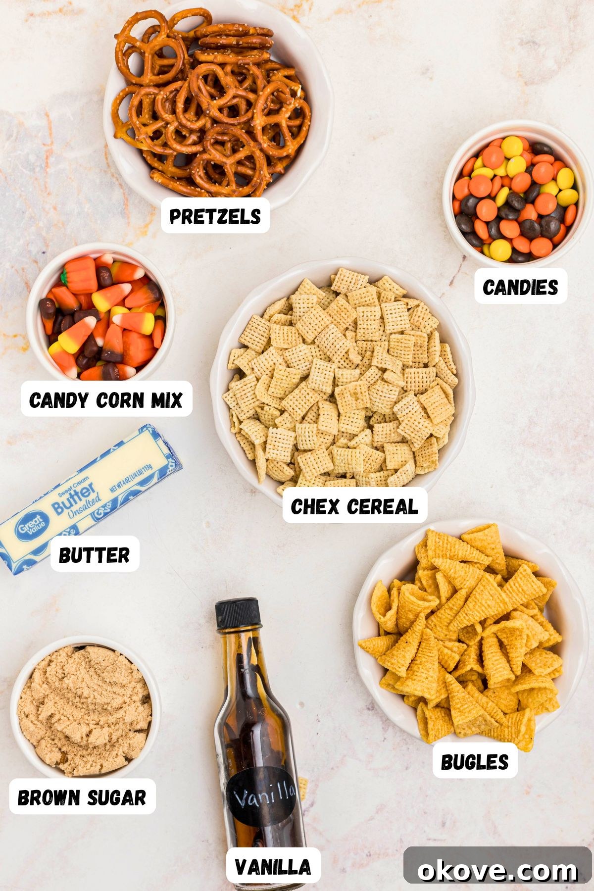 Spooky Halloween Chex Mix with Candy Corn and M&Ms 3 Candy corn, chex mix, bugles, pretzels, brown sugar, butter, and vanilla, in small bowls on a marble table.