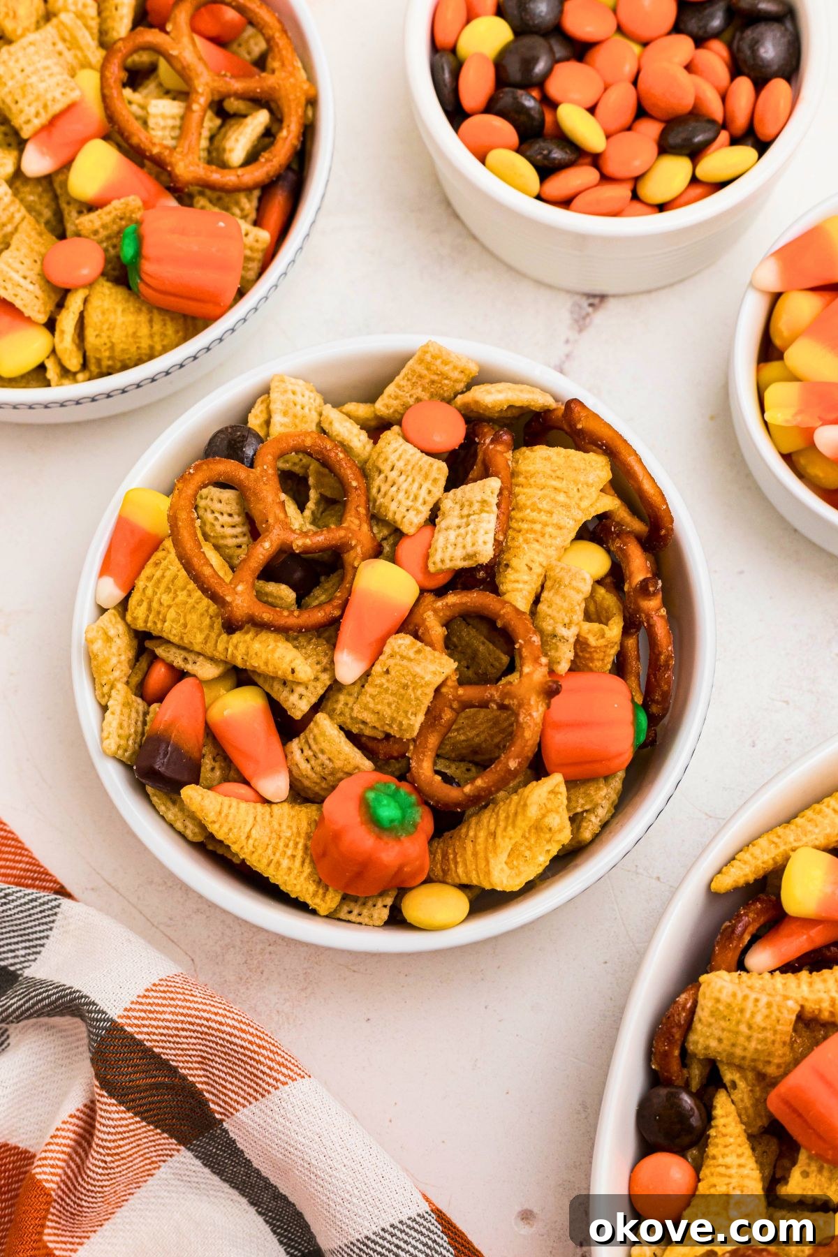Spooky Halloween Chex Mix with Candy Corn and M&Ms 8 Chex mix cereal, pretzels, candies, and other ingredients, mixed together, and served in small bowls on a marble table.