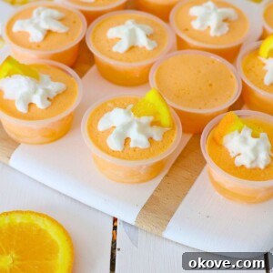 Orange creamsicle jello shots topped with whipped cream.