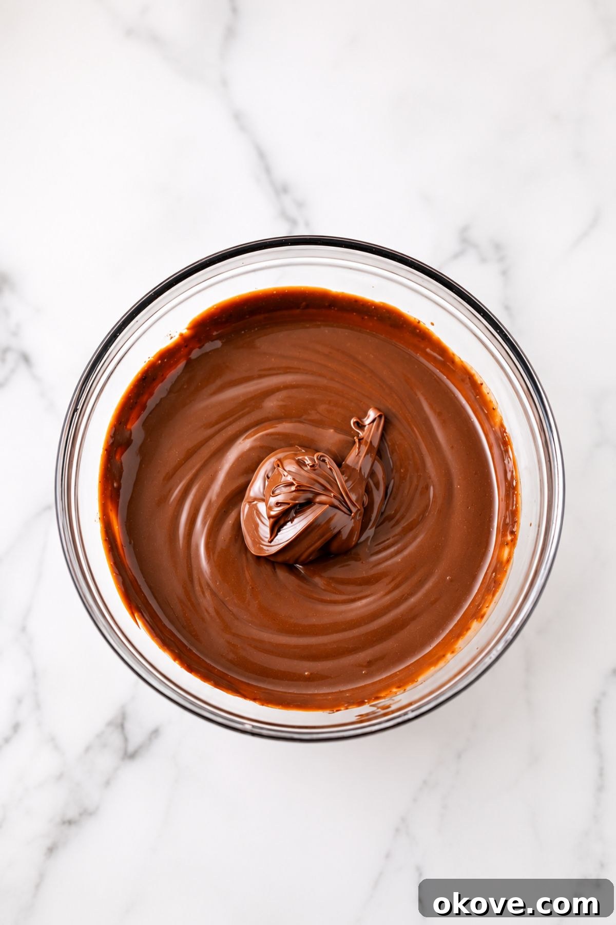 Large mixing bowl, filled with creamy chocolate pudding and a large portion of Nutella spread, before mixing together.