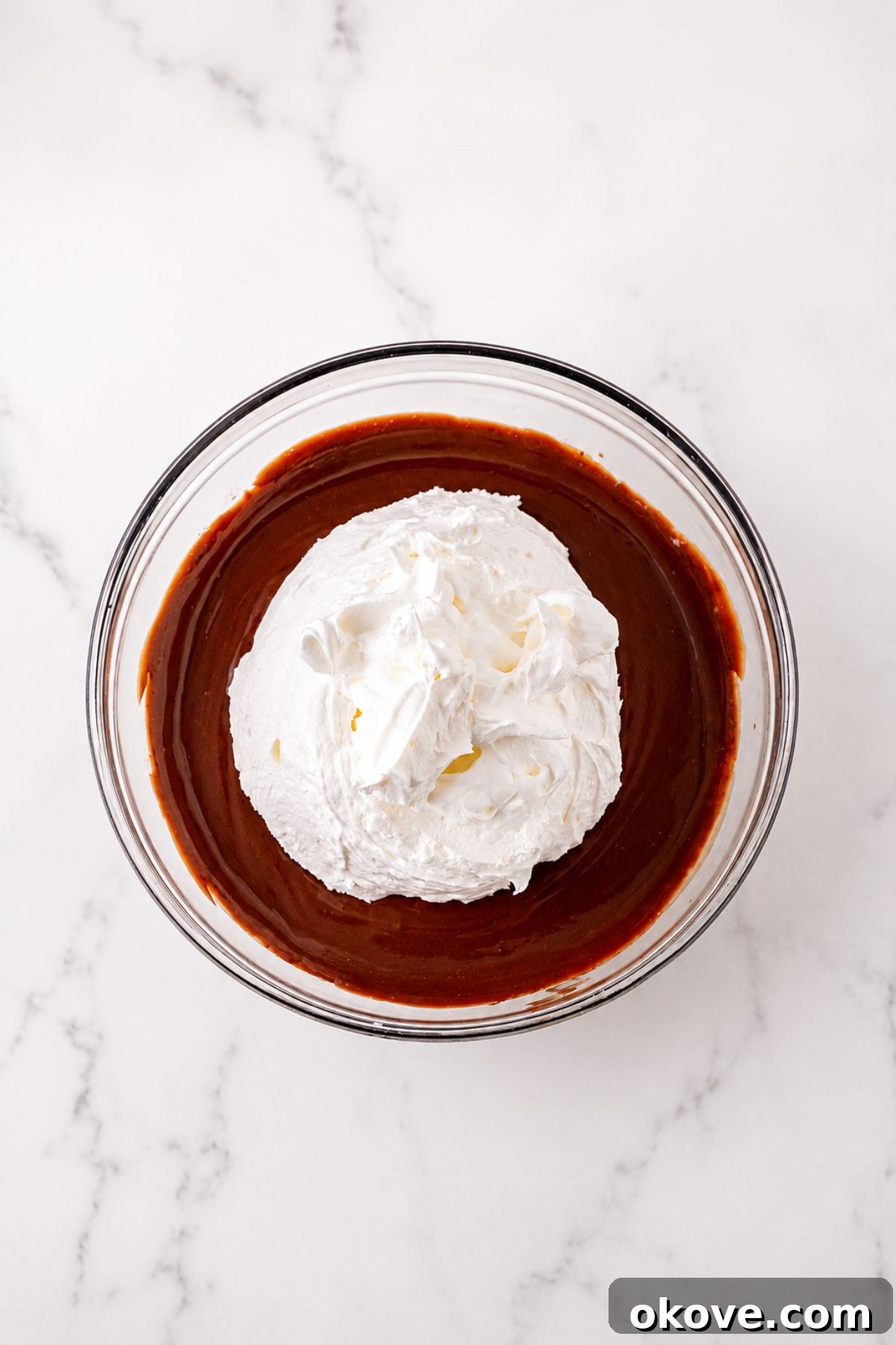 Large clear mixing bowl, filled with pudding, then topped with whipped cream, before mixing together.