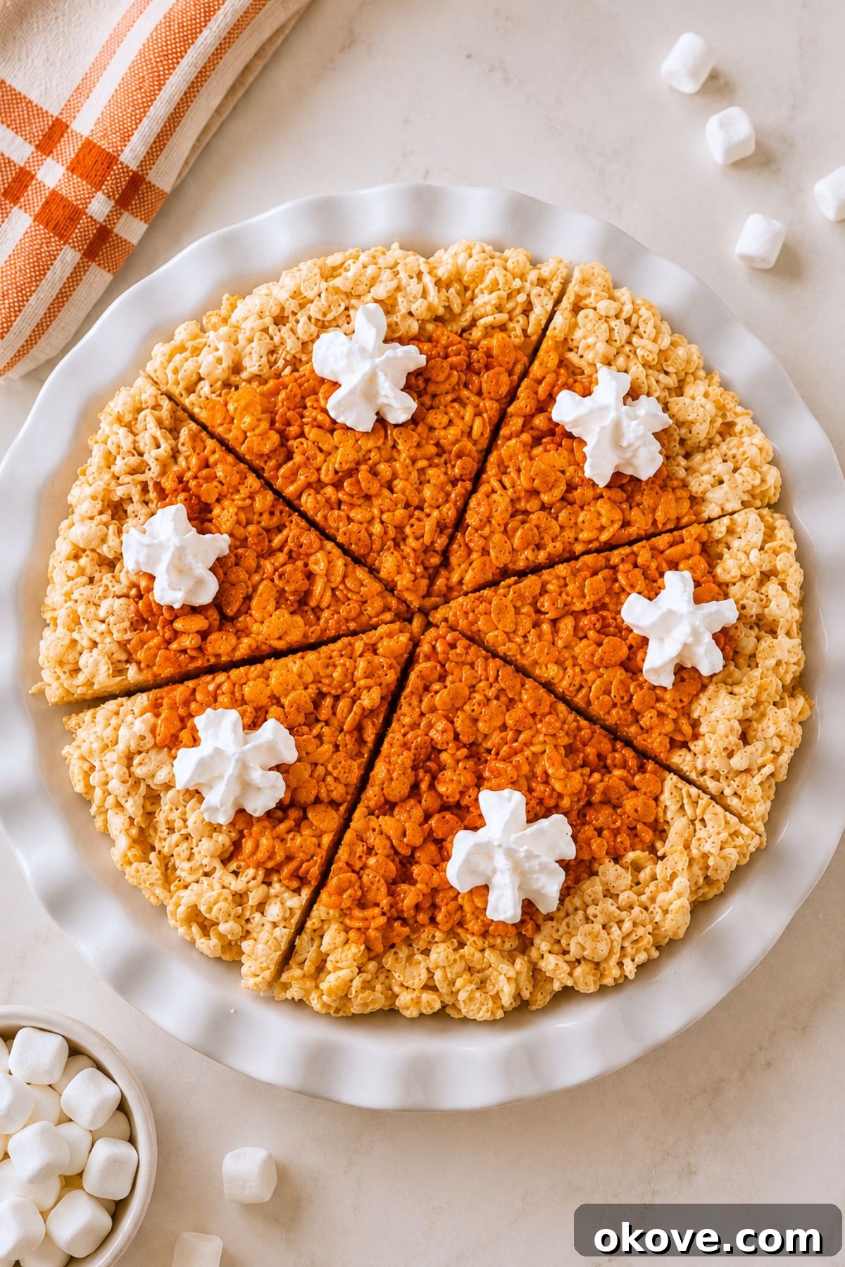Whole pie of krispie treats in a pie plate, after cutting, on a marble table.