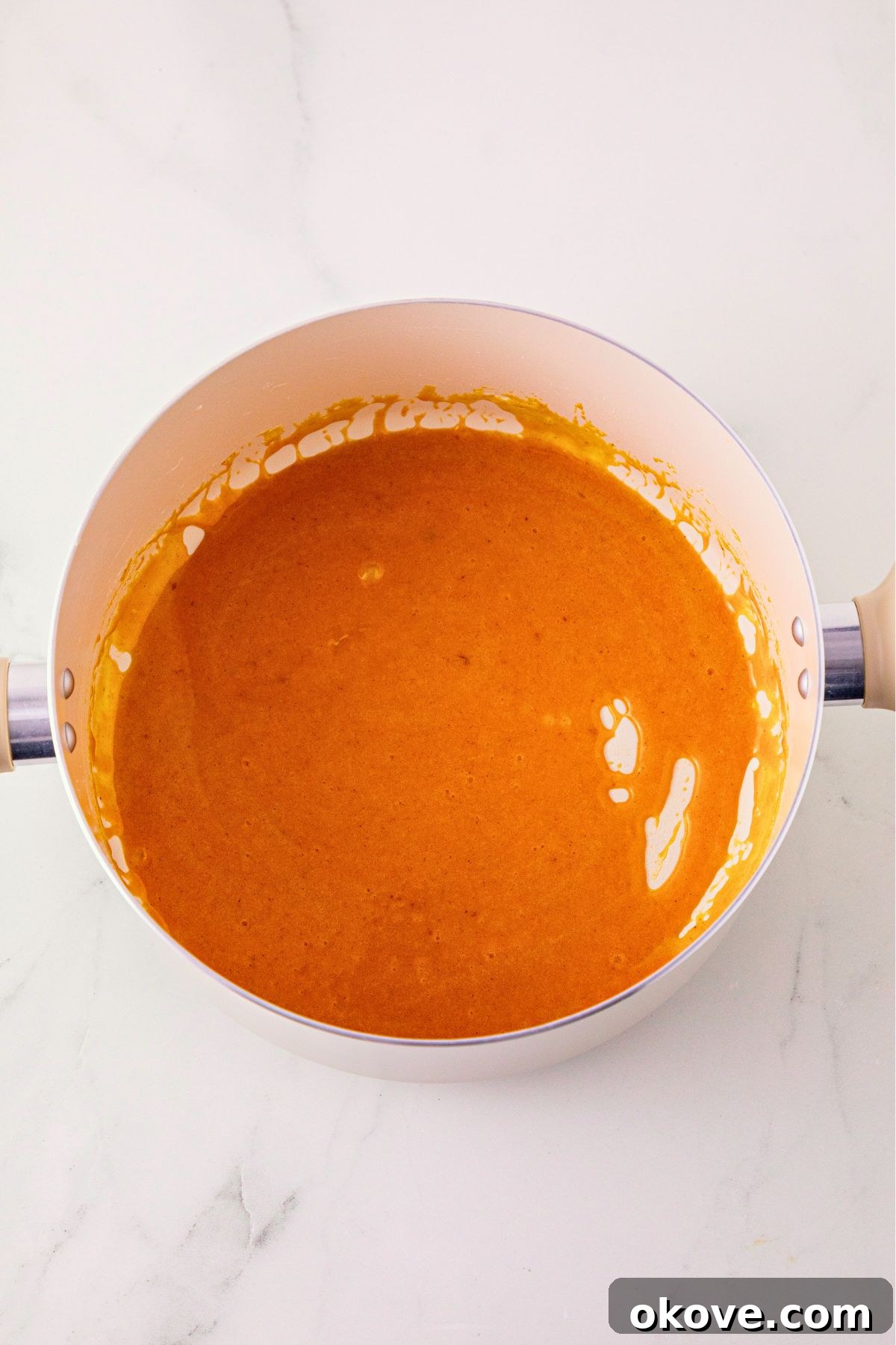 Marshmallows, butter, and pumpkin puree, mixed with orange food gel, in a large bowl.