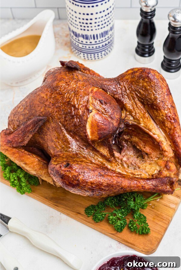 Golden smoked turkey on a brown wooden cutting board, with parsley next to it as a garnish.