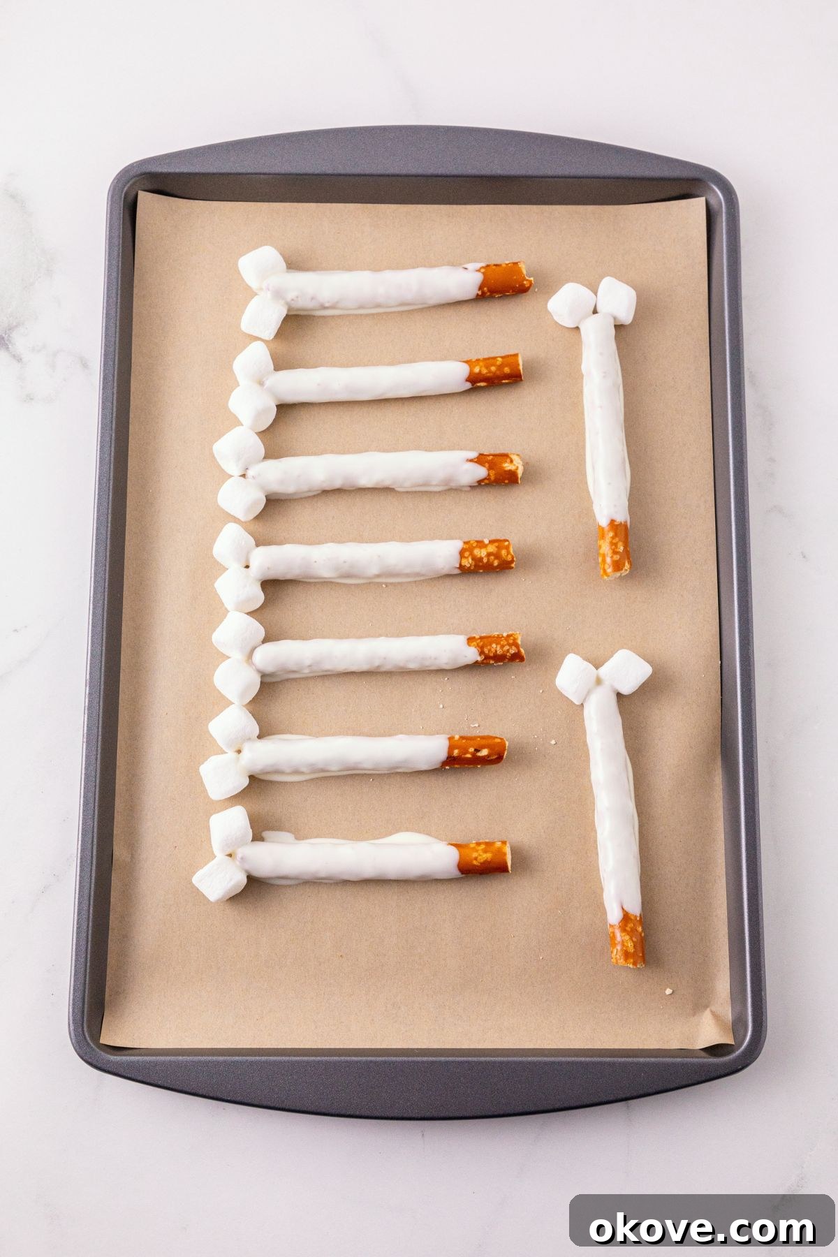 Pretzel Rods dipped in white chocolate, placed on a parchment paper lined baking sheet to harden. 