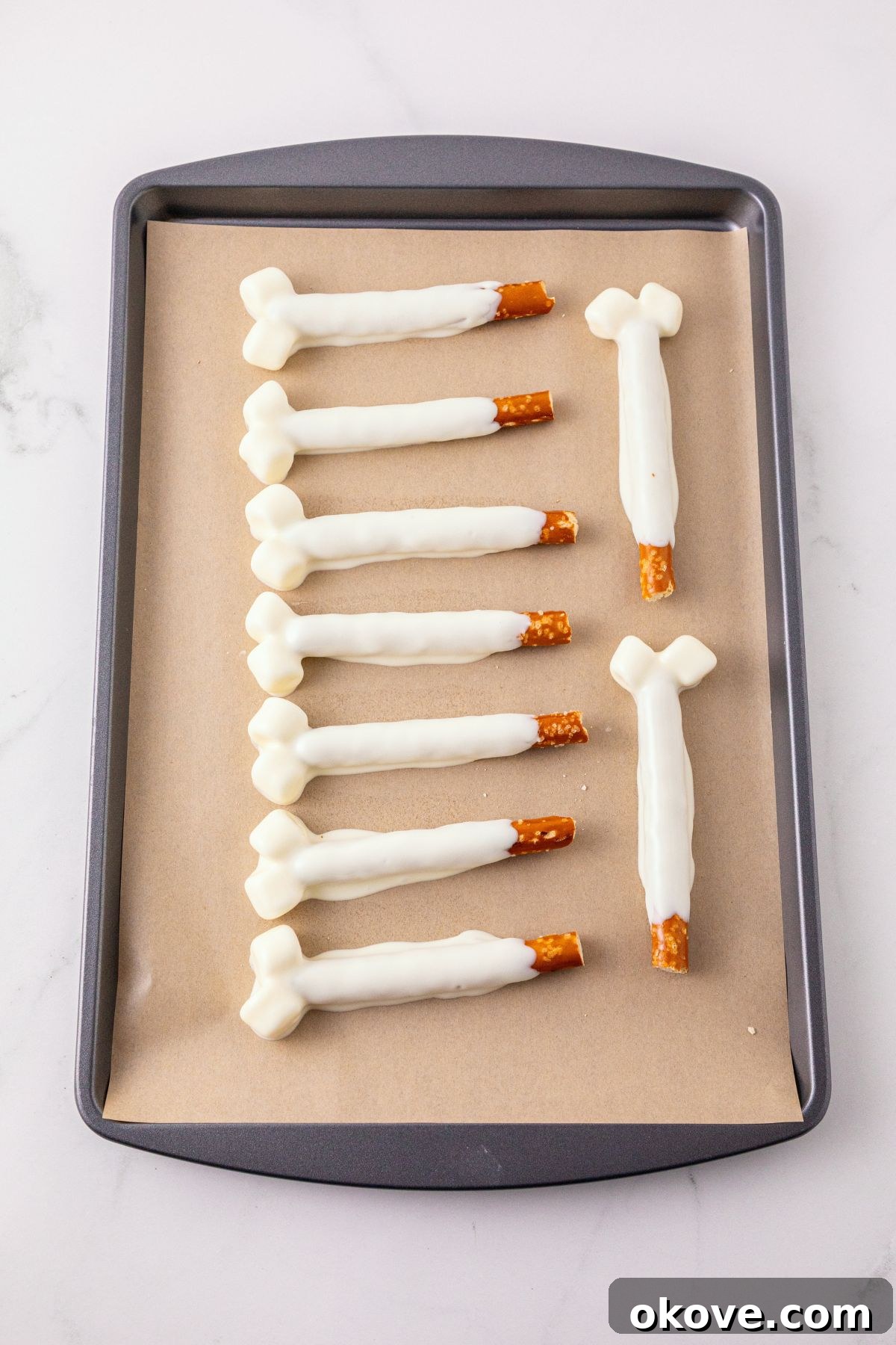 Pretzel rods and marshmallows double dipped in melting chocolate, then placed on parchment paper lined baking sheet to harden. 