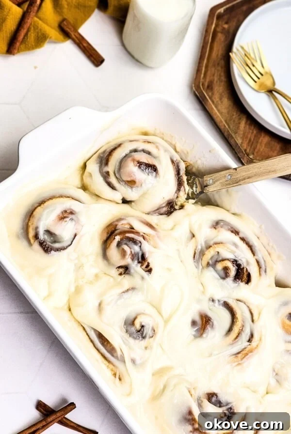 Gooey rolls in a white baking dish with frosting on top.