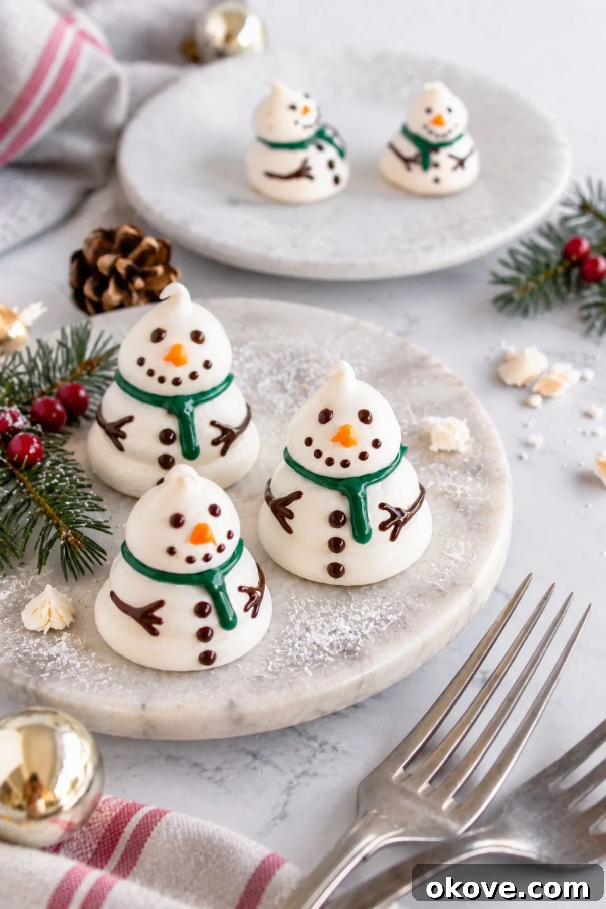 Baked snowmen on a white plate with holiday decorations around the table.