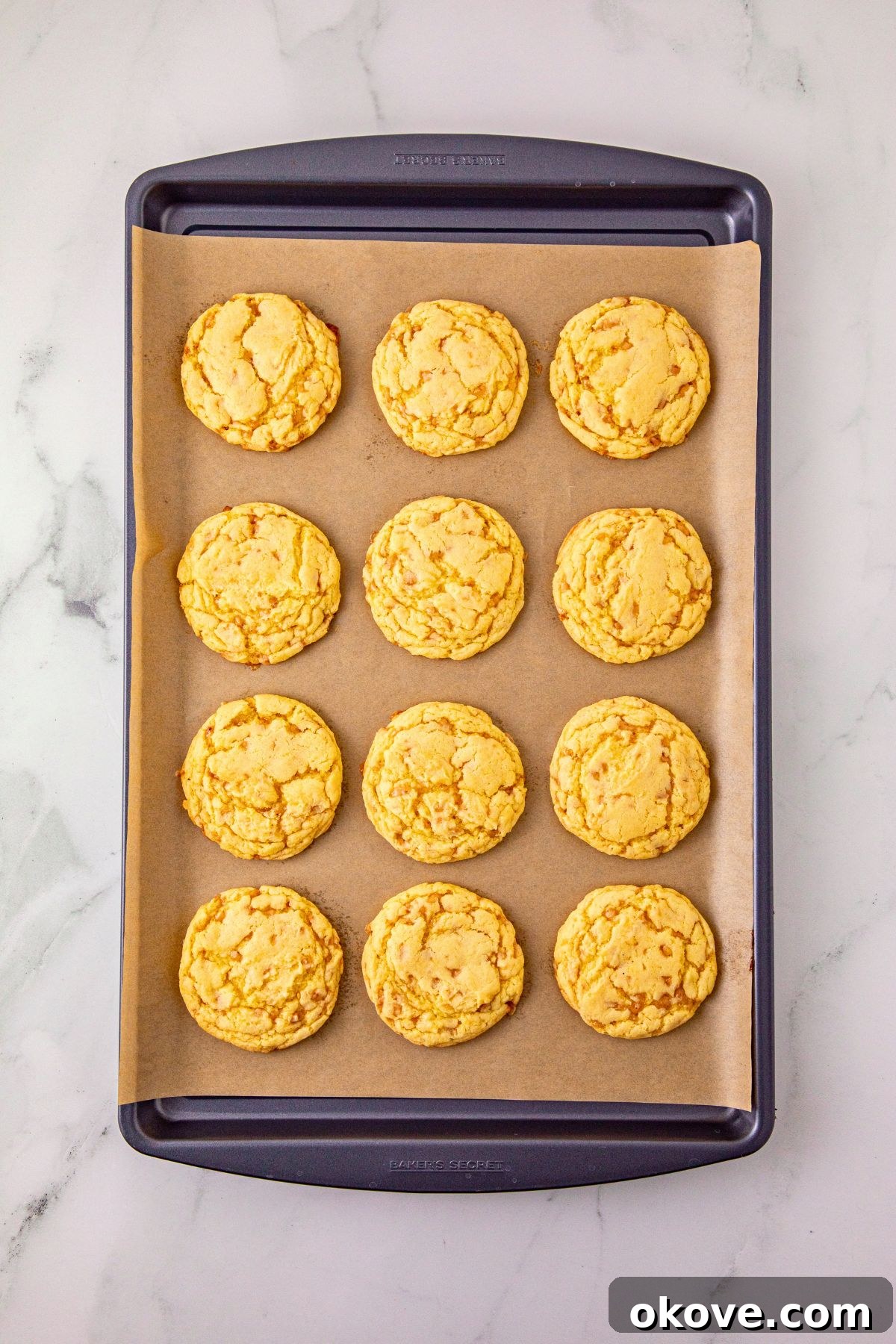 Baked cookies on a baking sheet lined with parchment paper, on a marble table. 