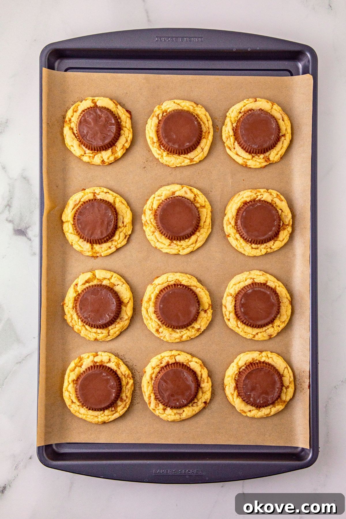 Vanilla cake mix cookies on a baking sheet, topped with peanut butter cup. 