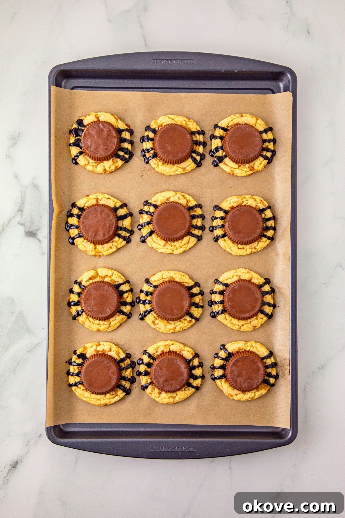 Baked cookies with a peanut butter cup placed on top of each cookie for the spider body.