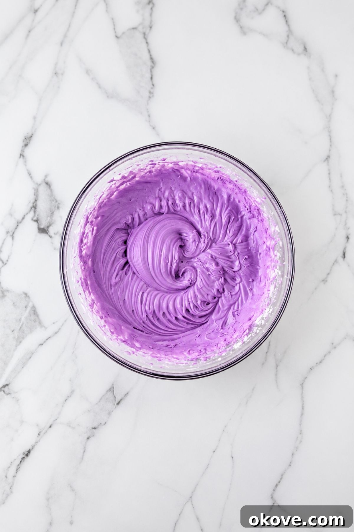 Purple Frosting in a clear glass mixing bowl. 